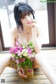 A woman sitting on a wooden floor holding a vase of flowers.