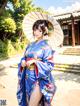 A woman in a blue kimono holding an umbrella.