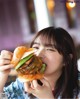 A woman is eating a hamburger with an egg on it.