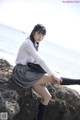 A woman sitting on a rock by the ocean.