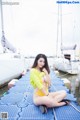 A woman in a yellow bathing suit sitting on a dock.