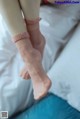 A woman is sitting on a bed with her feet up.