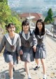 A group of young women in school uniforms walking down a street.